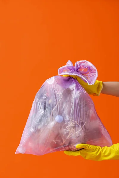 Mãos Femininas Luvas Borracha Segurando Saco Lixo Completo Fundo Laranja — Fotografia de Stock