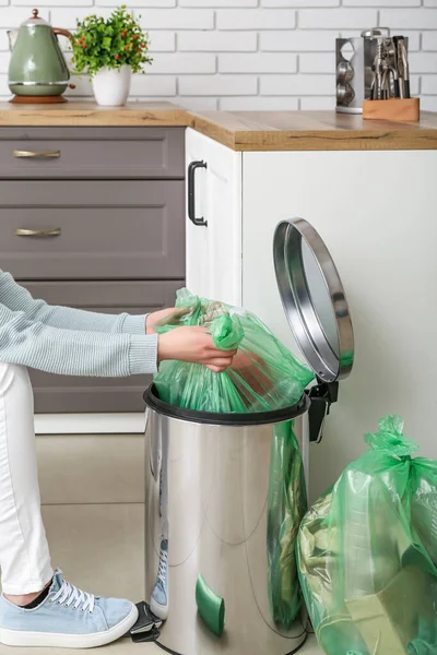 台所のゴミ箱からフルゴミ袋を取る女性 — ストック写真