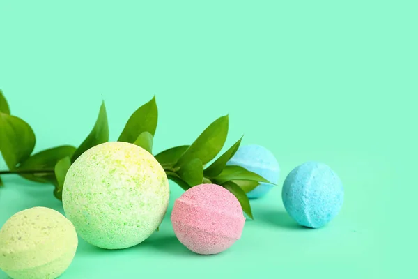 Bath bombs with plant branch on color background, closeup