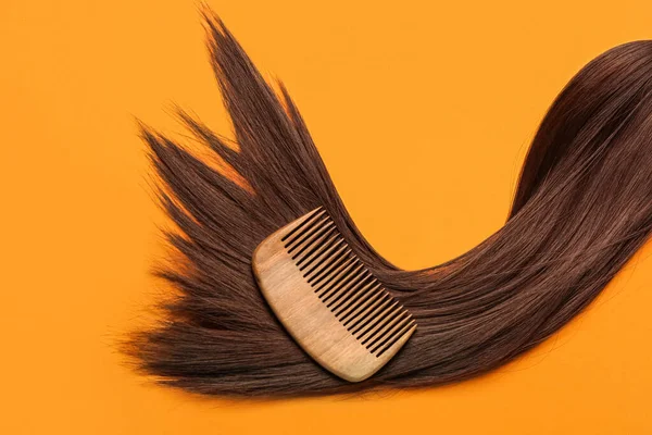 Brown hair with comb on color background
