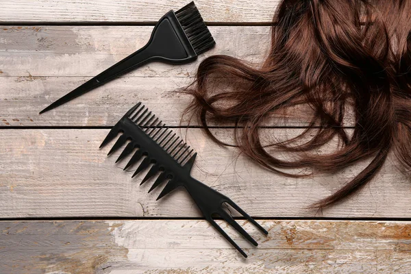 Brown hair with brushes on wooden background