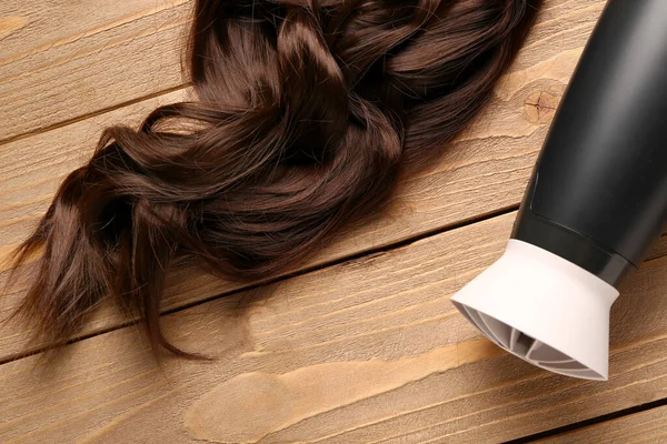 Lockige Braune Haare Mit Trockner Auf Hölzernem Hintergrund Nahaufnahme — Stockfoto