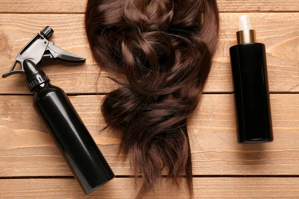 Curled brown hair with sprays on wooden background