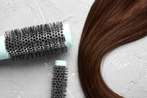 Brown hair with round brushes on grunge background, closeup