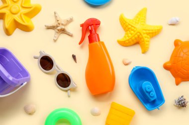 Plaj aksesuarları ve bej arka planda deniz kabukları olan bebek için güneş kremi.