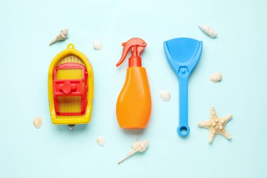 Plaj oyuncakları ve mavi arka planda deniz kabukları olan bebek için güneş kremi.