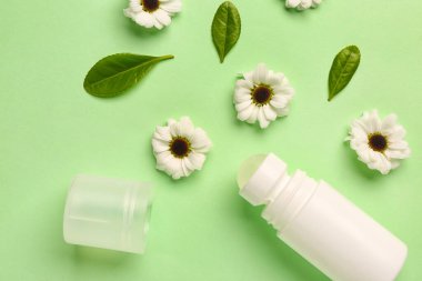 Çiçekli deodorant ve açık yeşil arka planda yapraklar