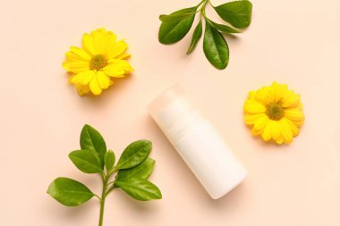 Çiçekli deodorant ve bej arkaplanda dallar