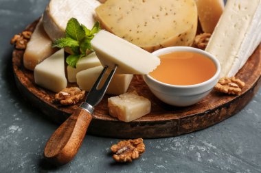 Farklı tipte peynir ve bal içeren tabaklar mavi arka planda, yakın plan.