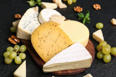 Koyu arka planda farklı çeşit lezzetli peynirli ahşap tahta.