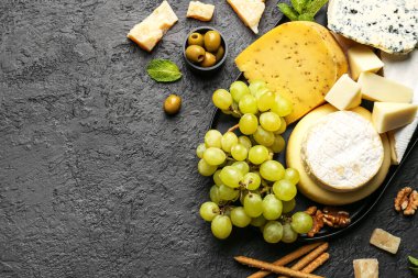 Farklı türde lezzetli peynir ve üzümlü tepsi koyu arkaplanda