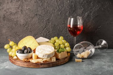 Farklı çeşit lezzetli peynirler, üzümler ve masada şarap.