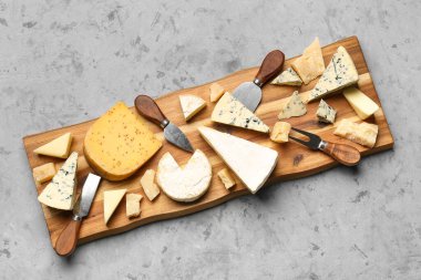 Ahşap tahta tahta, arkaplanda farklı çeşit lezzetli peynirler var.