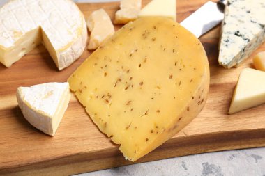 Masada lezzetli peynirli ahşap tahta, yakın plan.