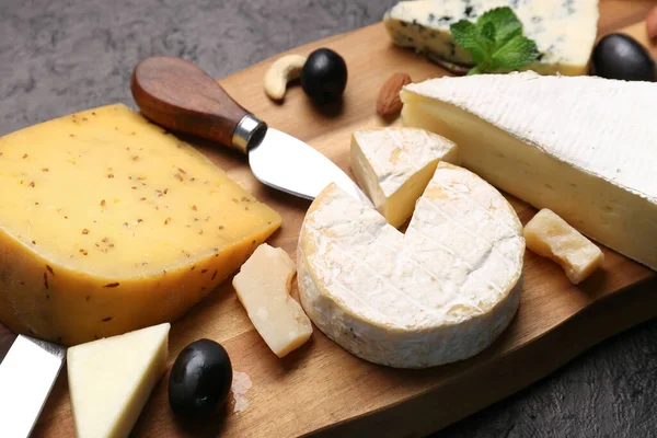 木制木板 不同类型的奶酪 深色底色 — 图库照片