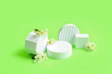 Dekoratif podyumlar ve yeşil arka planda beyaz çiçekler