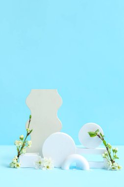 Dekoratif podyumlar ve mavi arkaplanda çiçek açan dallar