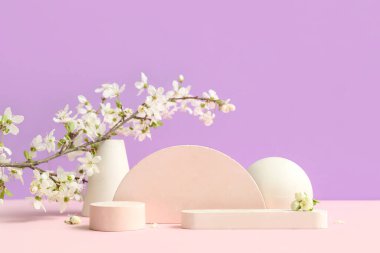 Eflatun arka planda dekoratif podyumlar ve çiçek açan şubeler