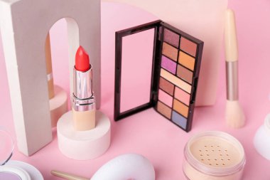 Pembe arka planda dekoratif sıva podyumları ve kozmetik ürünleri