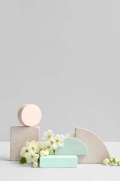 stock image Decorative podiums and blooming branch on grey background