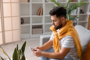 Young bearded man using mobile phone at home