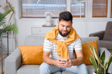 Young bearded man using mobile phone at home