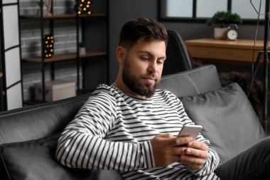 Young bearded man using mobile phone in office