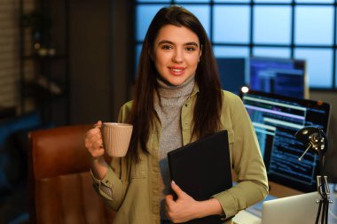 Genç bayan programcı ofiste kahve içiyor.