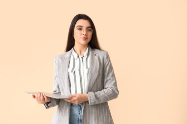 Bej arka planda dizüstü bilgisayarı olan genç bir kadın programcı.