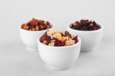 Beyaz arka planda farklı kurutulmuş meyve çaylarıyla dolu kaseler.