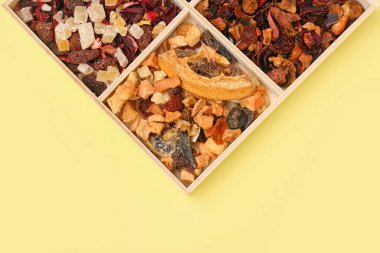 Sarı zemin üzerinde farklı kurutulmuş meyve çayı olan tahta.