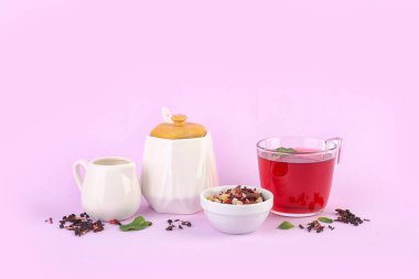 Kurumuş meyve karışımı ve pembe arka planda çay setiyle kompozisyon