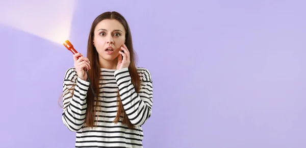 stock image Scared woman with flashlight on lilac background with space for text