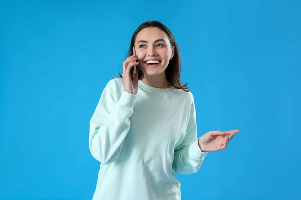 Mladá Žena Mluví Mobilním Telefonem Modrém Pozadí — Stock fotografie