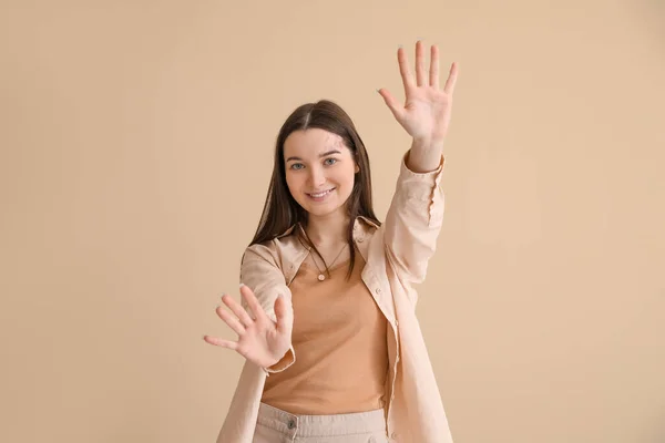 Junge Frau Zeigt Hände Auf Beigem Hintergrund — Stockfoto