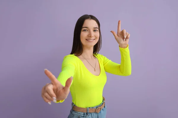 Mujer Joven Con Camisa Brillante Apuntando Algo Sobre Fondo Lila —  Fotos de Stock
