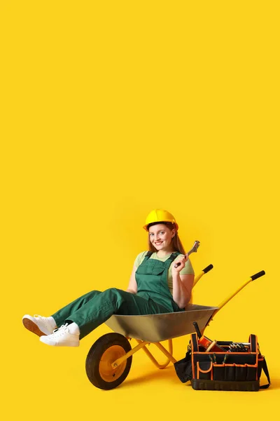 Female Builder Tool Sitting Wheelbarrow Yellow Background — Stock Photo, Image