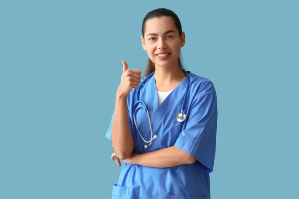 Médica Com Estetoscópio Mostrando Polegar Para Cima Fundo Azul — Fotografia de Stock