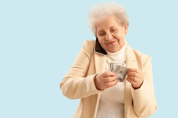 Mulher Sênior Com Dinheiro Falando Por Telefone Celular Fundo Azul — Fotografia de Stock
