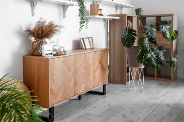 Masası, rafları ve Monstera bitkileriyle aydınlık oturma odasının içinde.