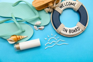 Güneş kreminden yapılmış kompozisyon, halka şamandırası, ahşap uçak, parmak arası terlik ve mavi arka planda deniz kabuğu.