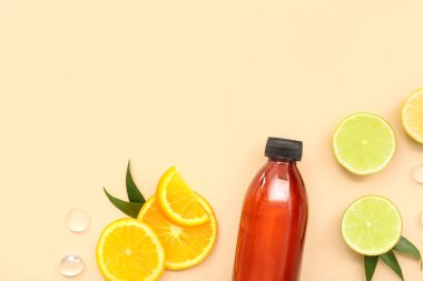 Meyve dilimleri ve bej arka planda cam taşlar olan bir şişe kozmetik ürünü.