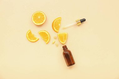 Pipetli bir şişe ve bej arka planda turuncu parçalar.