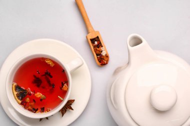 Gri zemin üzerinde bir fincan meyve çayı ile seramik çaydanlık