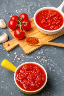 Lezzetli domates soslu kaseler ve mavi arka planda taze sebzeler.