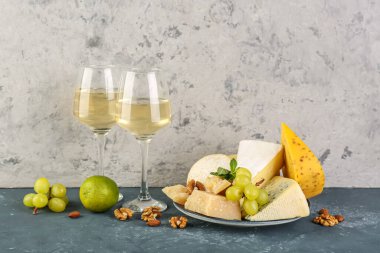 Farklı peynir, meyve ve bardaklarda şarap var.