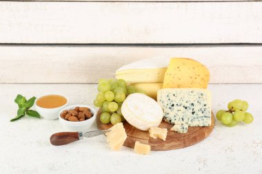 Masada farklı peynir, üzüm ve fındık çeşitleri olan ahşap tahta tahtalar.