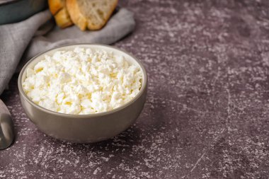 Koyu grunge arka planda lezzetli süzme peynirli kase