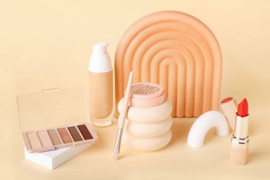 Sarı arka planda dekoratif sıva podyumları ve kozmetik ürünleri