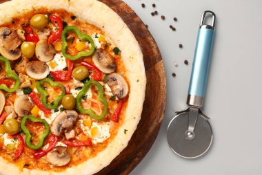 Gri arka planda sebzeli pizza ve kesicili tahta.